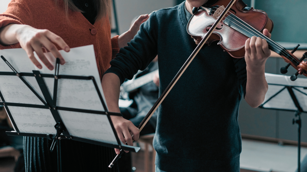 teacher giving violin lessons to student