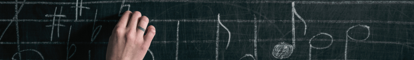 close up of teacher writing music notes on chalkboard