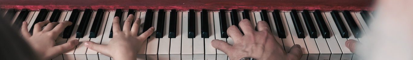 elder man and young child playing piano together